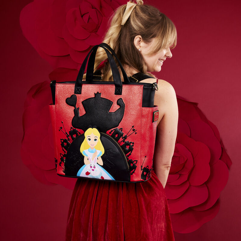 Image of woman in red dress wearing the Alice in Wonderland Convertible Tote as a backpack against a red background